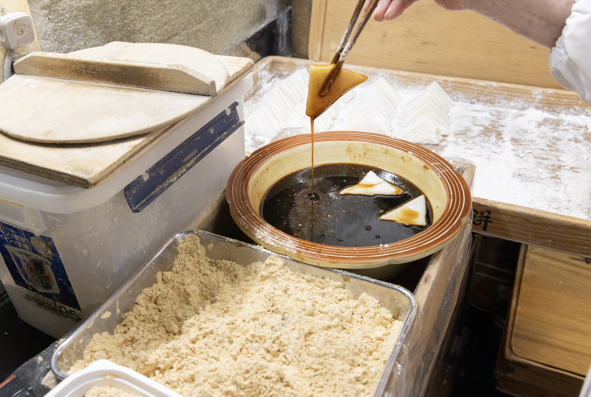 とろとろの黒蜜に三角の餅をつけて、きな粉に絡める。（「大吉餅」）